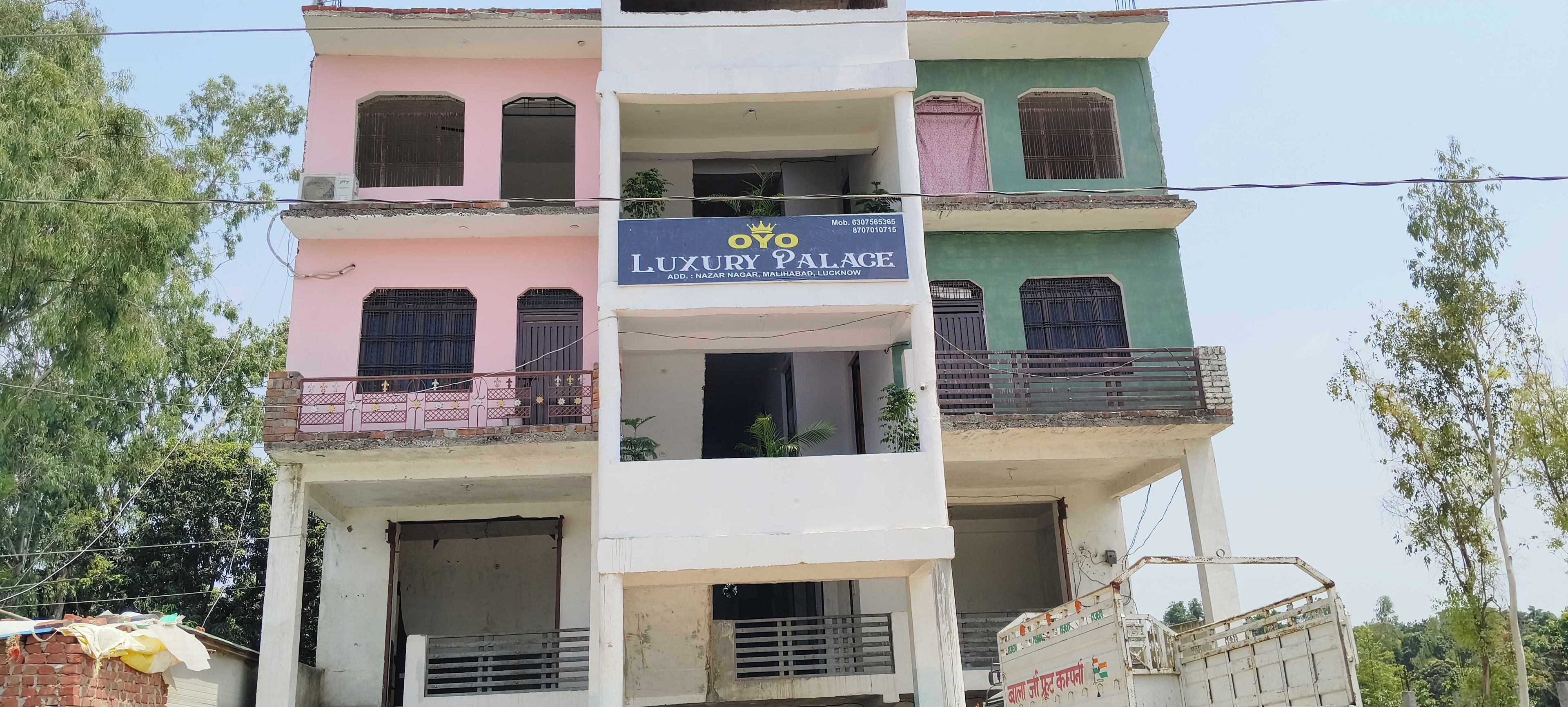 Een meerlaags gebouw met balkons en een bord met de tekst 'Oyo Luxury Palace'.