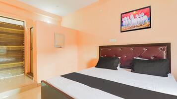 Een hotelkamer met een groot bed, een houten deur en een schilderij aan de muur.