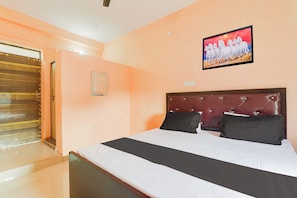 Een hotelkamer met een groot bed, een houten deur en een schilderij aan de muur.