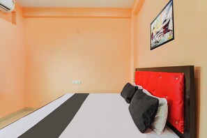 Quarto de hotel com cama, cabeceira vermelha e um quadro na parede.