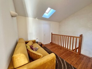 Une pièce avec un escalier en bois, un canapé, une lampe et une porte.