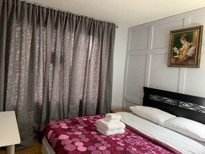 Une chambre d’hôtel avec un lit, des rideaux, un tableau et une lampe.