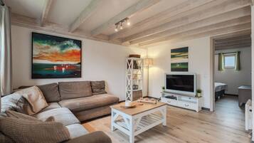 A living room with a sofa, coffee table, TV, and paintings on the wall.