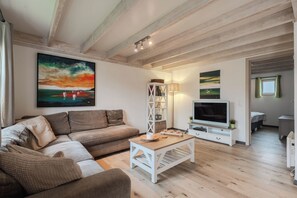 Un salon avec un canapé, une table basse, un téléviseur et des tableaux accrochés au mur.