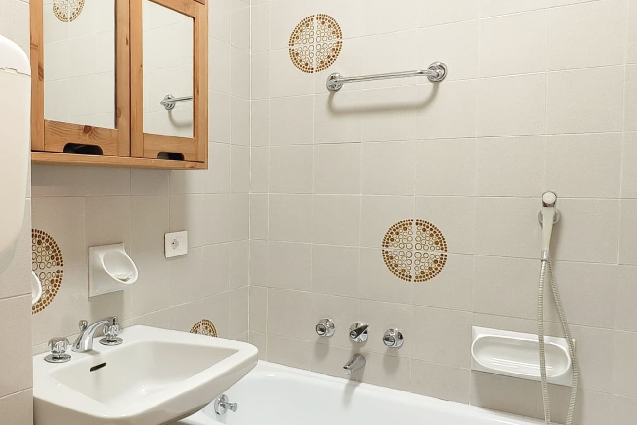 Une salle de bain équipée d’un lavabo, d’un miroir, d’un porte-serviettes et d’une douche.