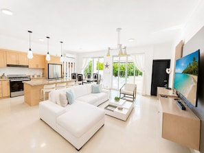 Un espacio habitable moderno con cocina, comedor y una gran pantalla de televisión.