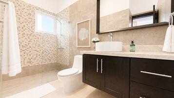 Un baño moderno con inodoro, tocador y zona de ducha.