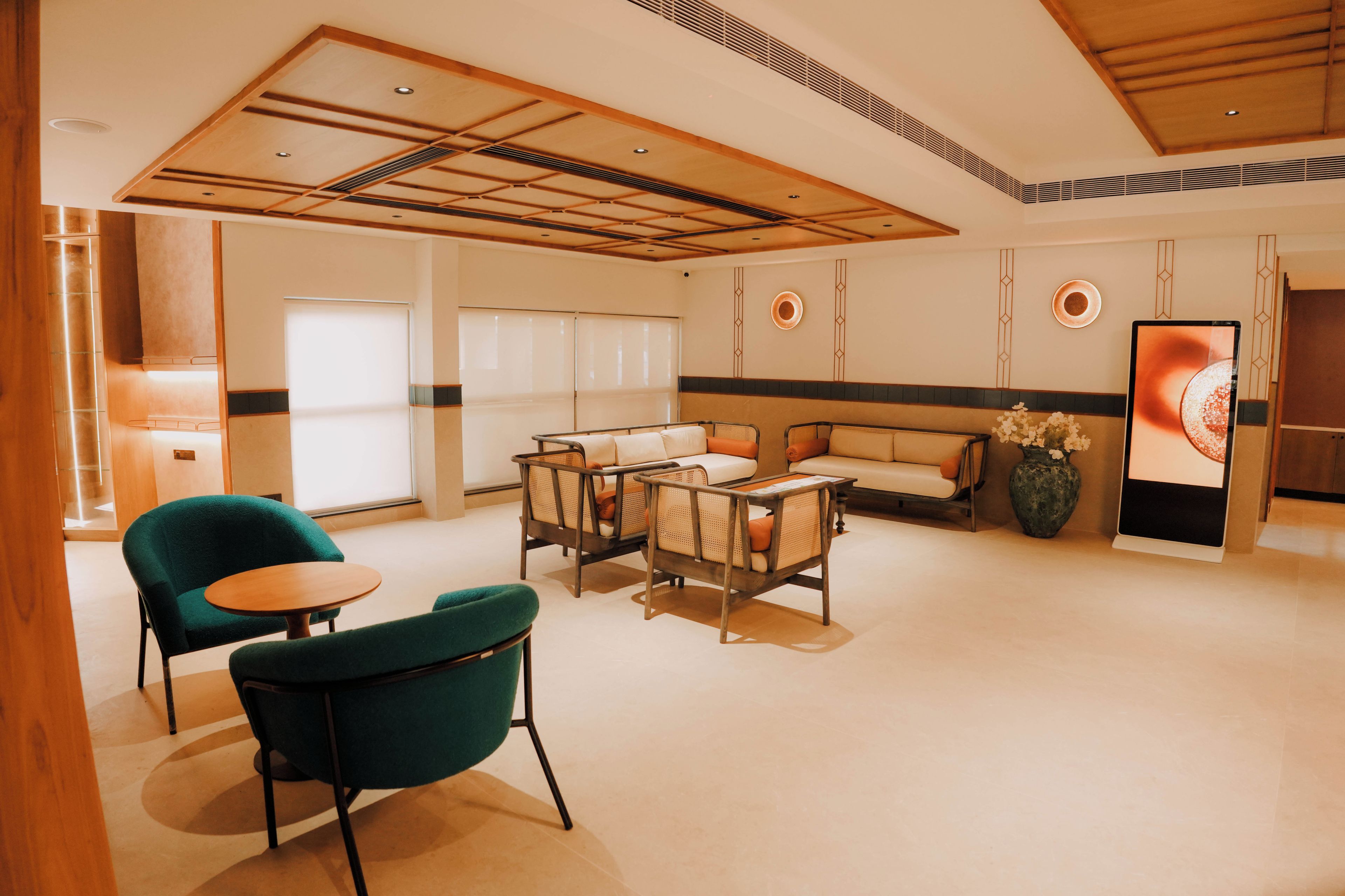 A modern hotel lobby with a seating area, a reception desk, and a large vase of flowers.