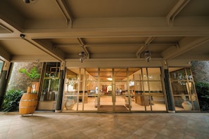 Entrada de hotel con puerta de vidrio, pared de piedra y piso de baldosas.
