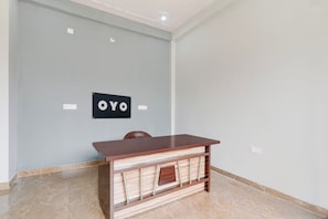 A room with a wooden desk, a chair, a light grey wall, and a sign with the letters 'OYO'. - Hotel O Little Star (Hasanganj)