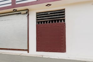 A building facade with a closed metal shutter and a decorative brown door. - Hotel O Little Star (Hasanganj)