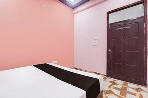 A room with a bed, a door, and a light switch on the wall. - Hotel O Little Star (Hasanganj)