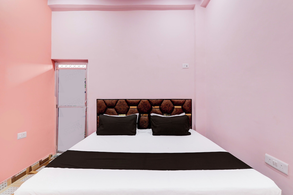 A single bed with a headboard, two pillows, a white bedspread, and a black blanket.