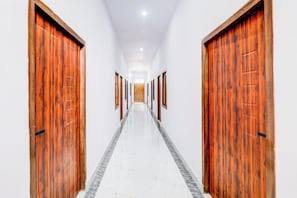 Um corredor com portas de madeira em ambos os lados, que leva a um quarto claro no final.