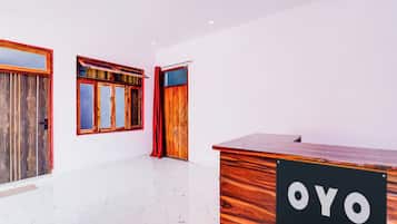 A reception desk with a sign, a wooden door, and a window with curtains.