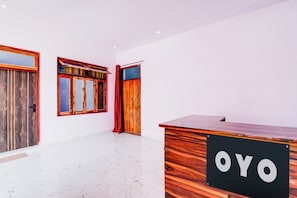 Um balcão de recepção com uma placa, uma porta de madeira e uma janela com cortinas.