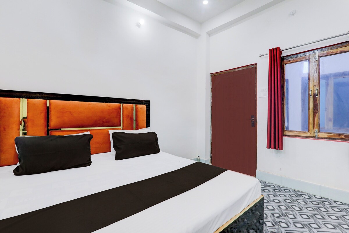 Een hotelkamer met een bed, een raam met gordijnen en een deur.