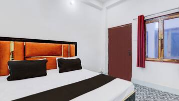 Een hotelkamer met een bed, een raam met gordijnen en een deur.