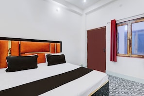 Een hotelkamer met een bed, een raam met gordijnen en een deur.