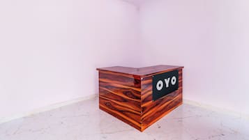 Un mostrador de recepción de madera con un letrero que dice 'OYO' en una habitación con paredes blancas y piso de mármol.