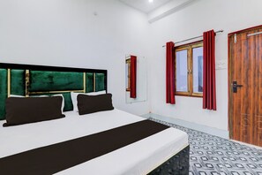 Een slaapkamer met een bed, een hoofdeinde, een raam met gordijnen en een deur.