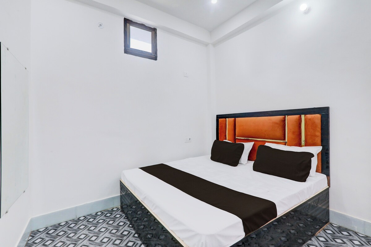 A hotel room with a bed, a small window, and patterned flooring.