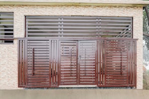 A building facade with a brick wall and a large metal gate with horizontal bars. - Hotel O Kp Guest House (Bara Banki)