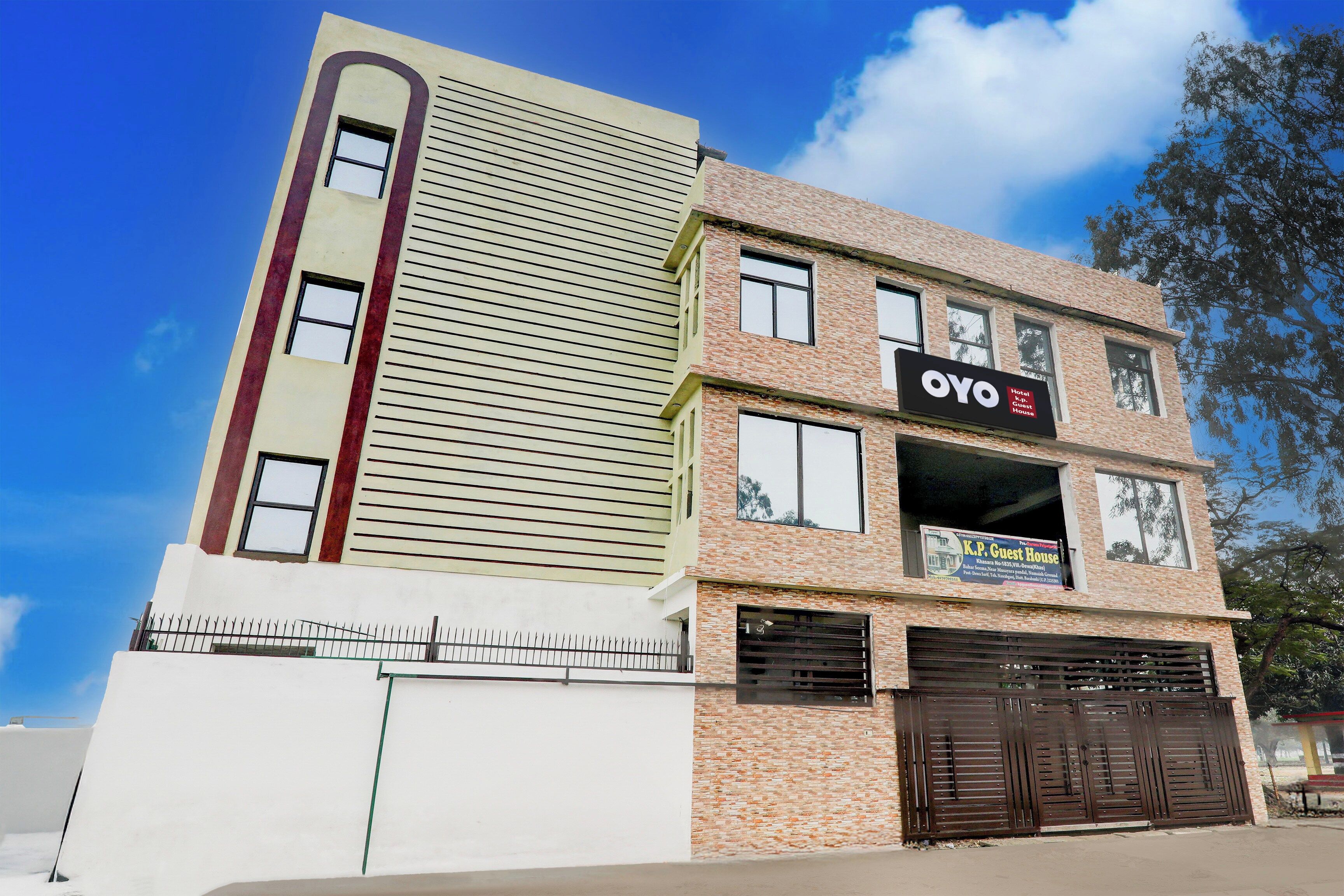 Un edificio de varios pisos con un llamativo rótulo de OYO Hotel, una entrada con portones y un cielo despejado.