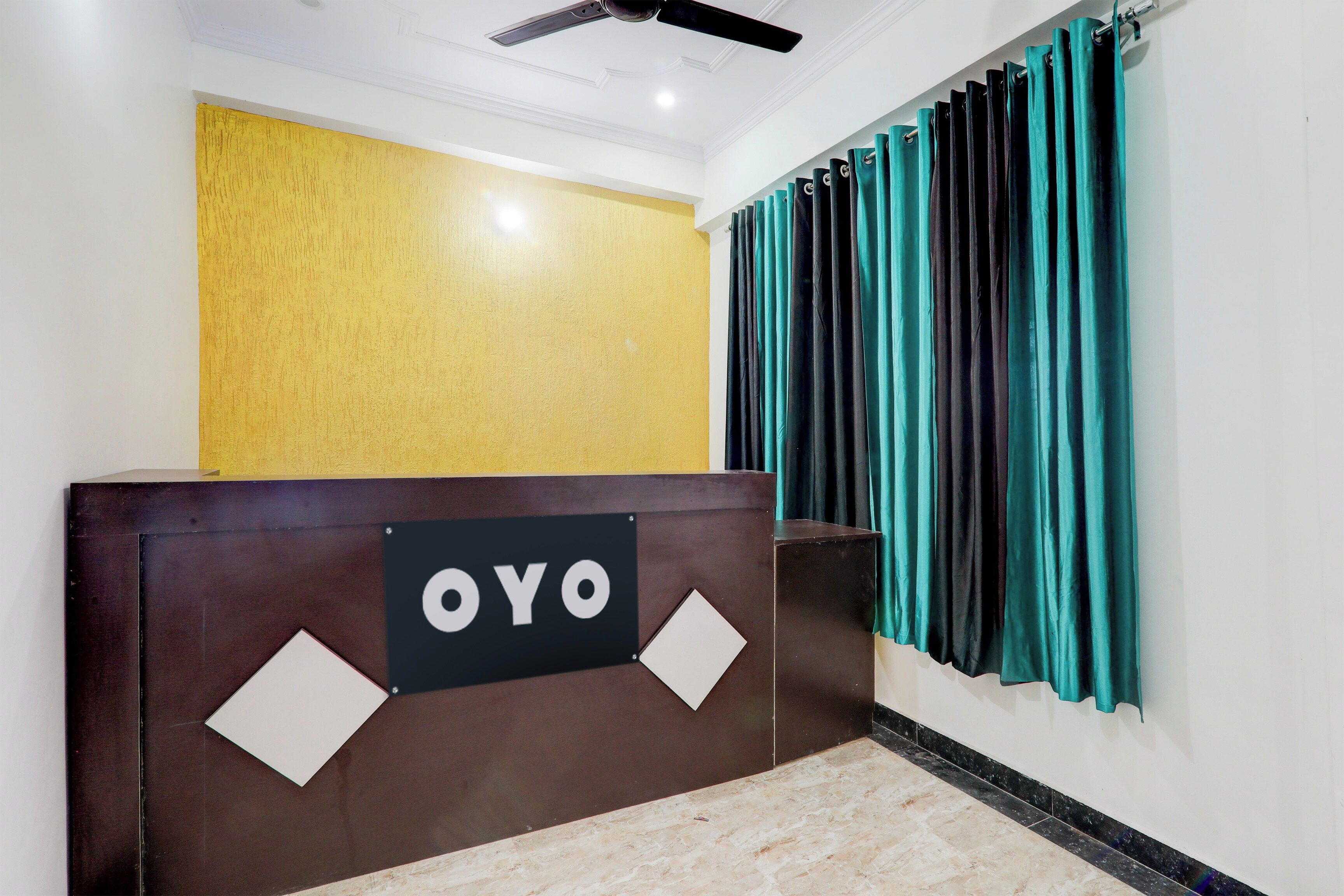 Una recepción con un cartel que dice 'OYO' y un juego de cortinas azul turquesa a la derecha.