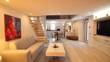 A modern living room with a sofa, coffee table, and a painting on the wall.