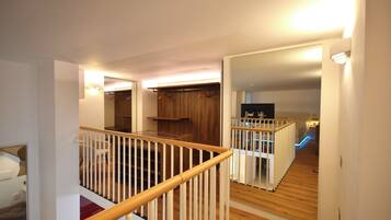 A multi-level interior with a wooden staircase, a mirrored closet, and a kitchen area.