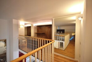 Een meerlaags interieur met een houten trap, een spiegelkast en een keukenhoek.