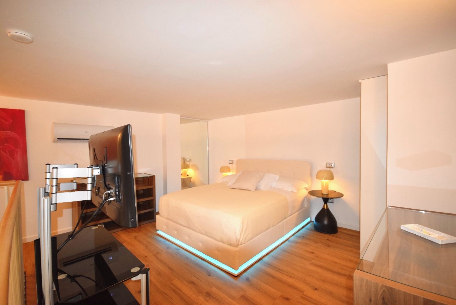Une chambre d’hôtel moderne équipée d’un lit, de lampes de chevet, d’un téléviseur à écran plat et d’un plancher en bois.