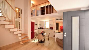 A modern apartment with a staircase, a dining area, and a kitchen.