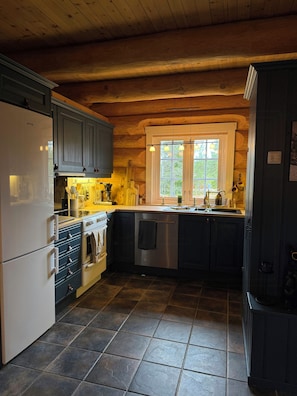 Eine Küche mit Holzbalkendecke, einer Edelstahl-Spüle und einem eingebauten Backofen.