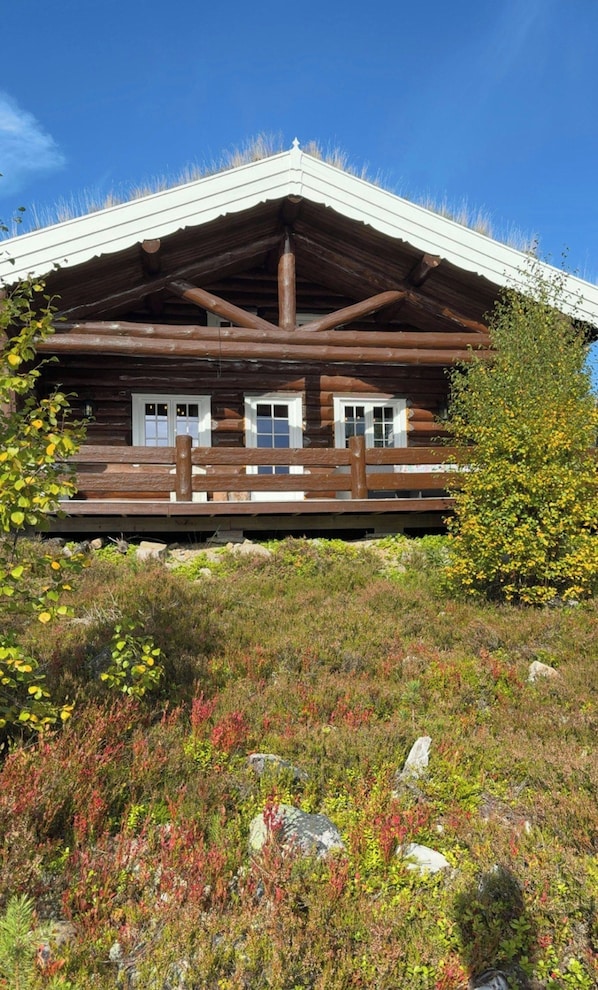 A log cabin with a porch, a pitched roof, and a clear sky.