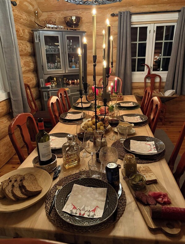 A dining room with a long table set for a meal, featuring candles, plates, glasses, and a bottle of wine. - Cabin in Trysil-Knuts Fjellverden with fireplace (Innlandet)