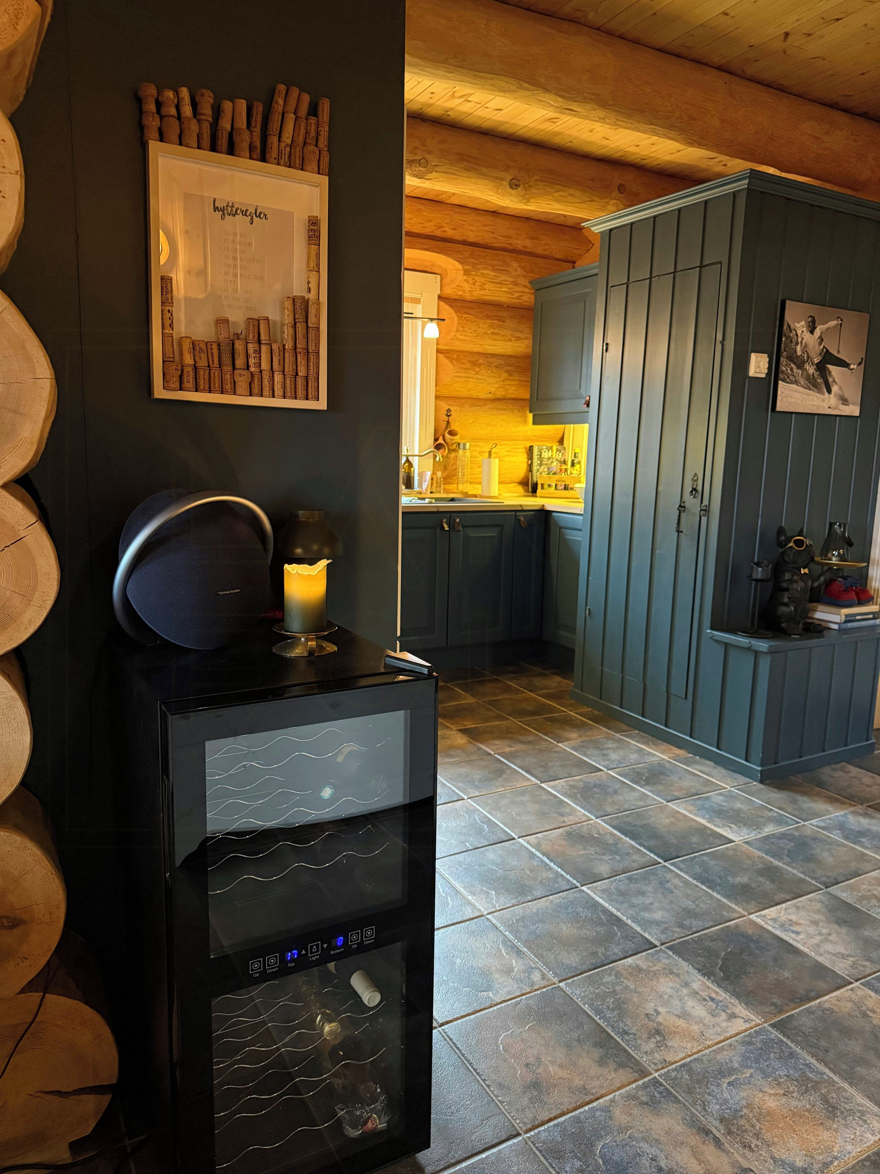 A kitchen with dark wooden cabinets, a black refrigerator, and a tiled floor.