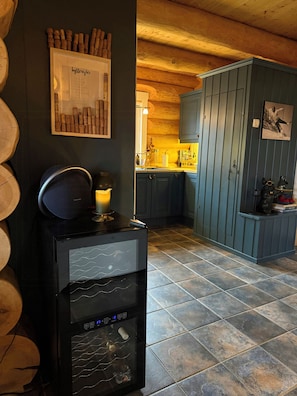 A kitchen with dark wooden cabinets, a black refrigerator, and a tiled floor.