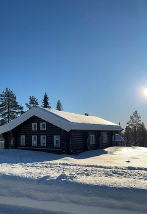 A log cabin with a snow-covered roof, surrounded by snow and trees. - Cabin in Trysil-Knuts Fjellverden with fireplace (Innlandet)