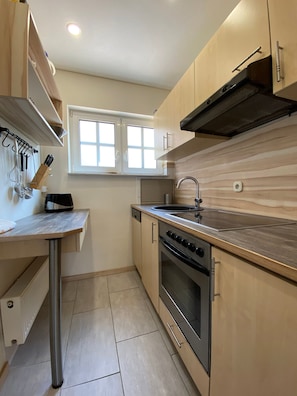 Une cuisine de taille réduite équipée d’une cuisinière, d’un four, d’un évier et d’une fenêtre.
