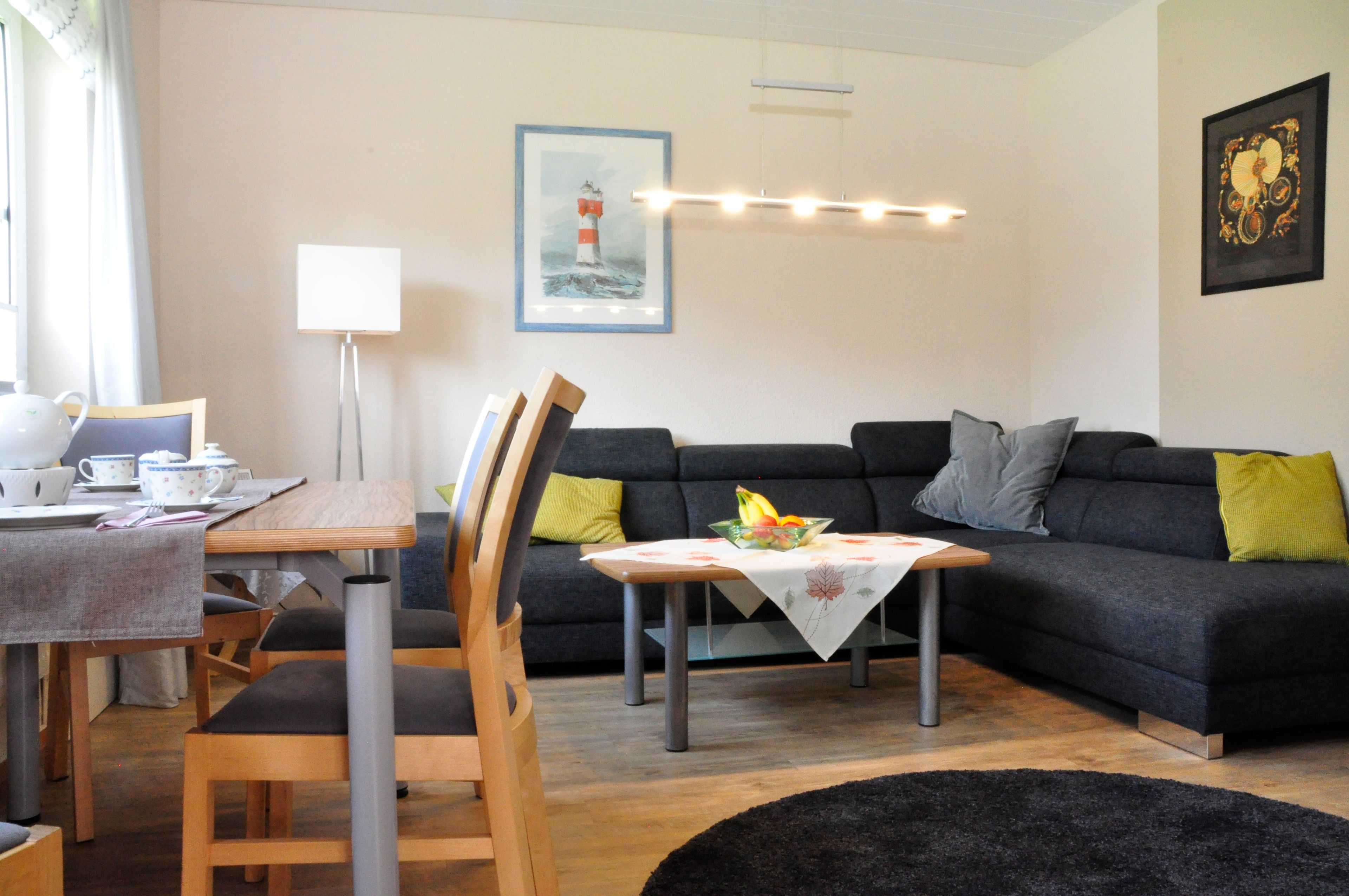Ein Wohnzimmer mit Essbereich, einer Couch, einem Couchtisch und einem Gemälde an der Wand.