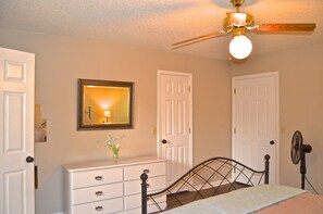 Un dormitorio con cama, cómoda, espejo y ventilador de techo.