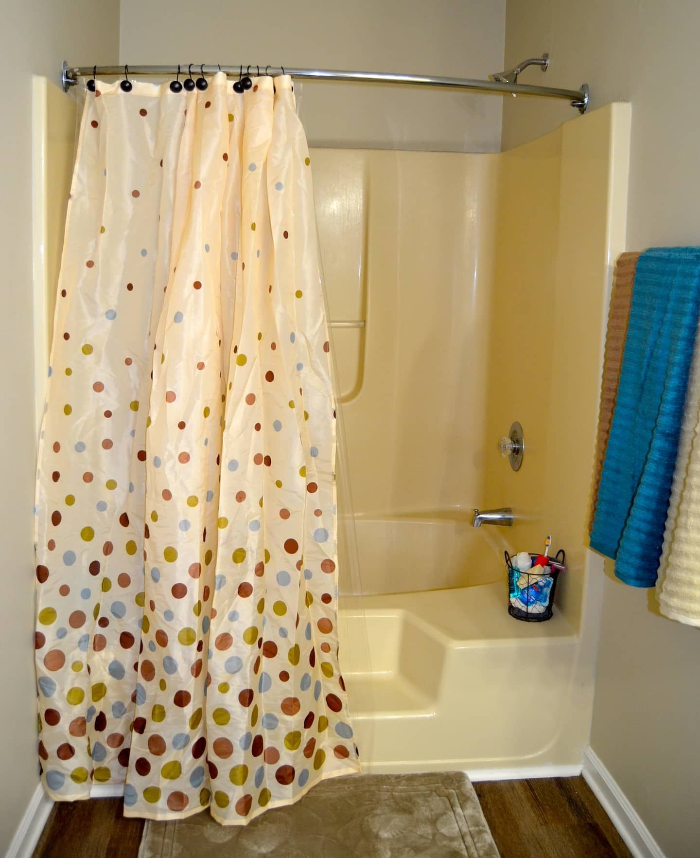 Ein Duschbereich mit vorzeigvoller Duschvorhang, einer Badewanne und einem kleinen Waschbecken mit einer Tasse Gegenstände.