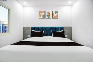 A hotel room with a large bed, a blue headboard, and three framed artworks on the wall. - Hotel O Shubh Inn 4 (Lucknow)