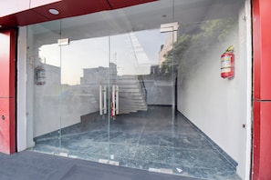 A glass door entrance with a fire extinguisher on the wall. - Hotel O Shubh Inn 4 (Lucknow)
