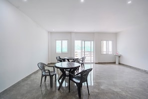 Een ruime kamer met een betegelde vloer, een ronde tafel met stoelen en een raam met uitzicht.