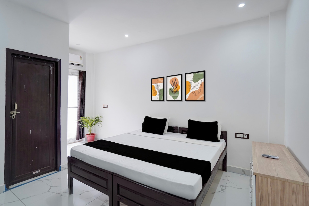 Un dormitorio con una cama, una mesita de noche, una planta en maceta y tres cuadros en la pared.