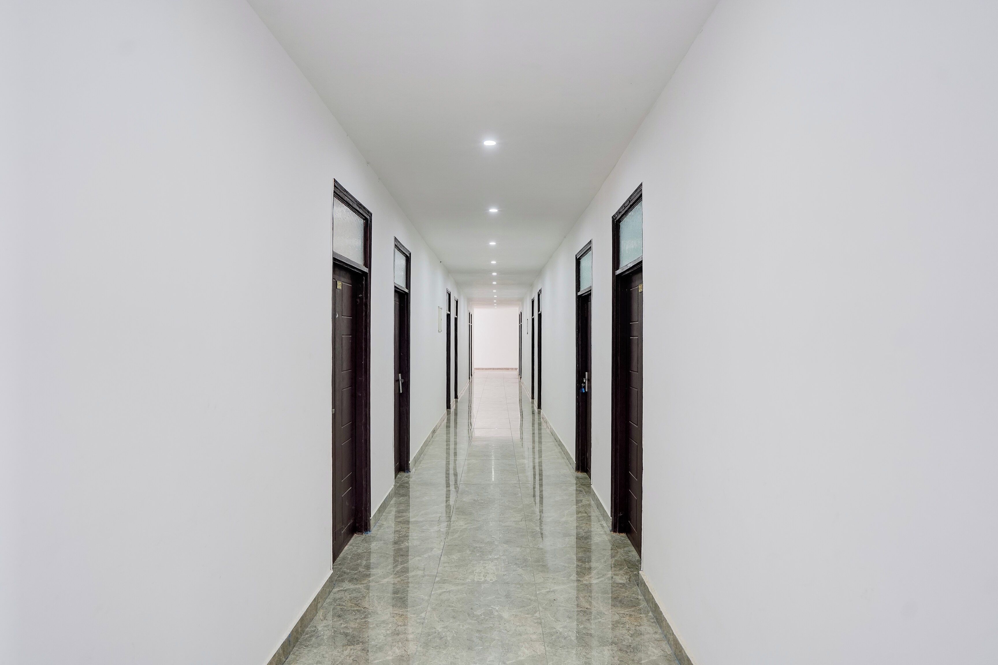 A long, narrow hallway with doors on both sides, leading to individual rooms.