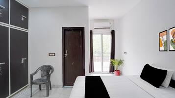 A bedroom with a bed, a chair, a wardrobe, a door, and a window.